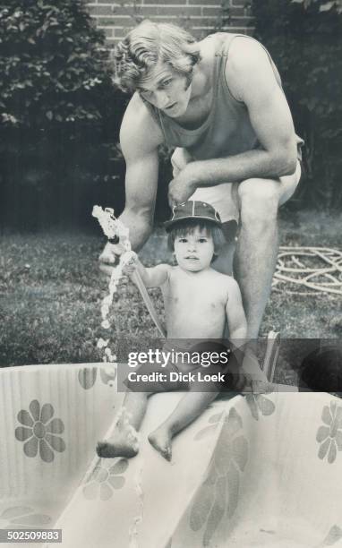 Daddy's laid up -- Goody! Toronto Argonaut quarterback Joe Theismann; kept bome with badly sprained foot; has some cooling fun with his son; Joe Jr.;...