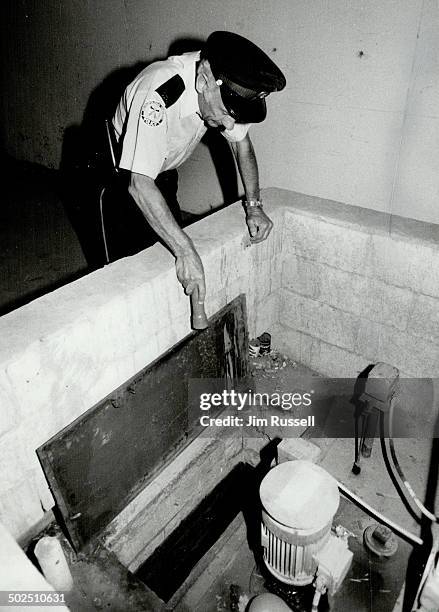 Intensive search: Metro police constable Terry Donovan inspects the sump pump collecting basin in the parking garage of the condominium where missing...