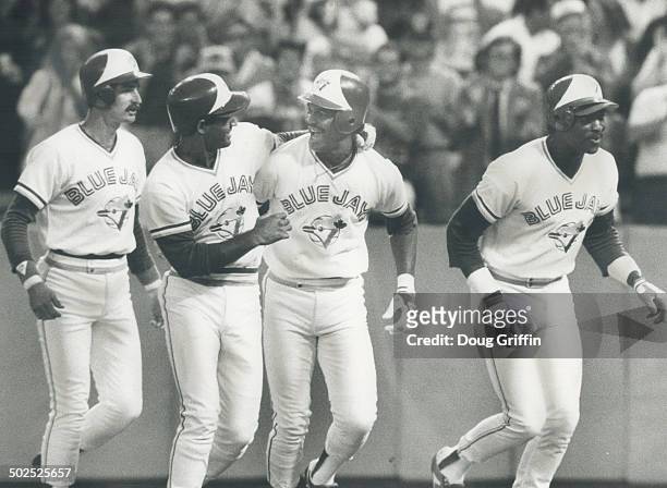 Happy flock: Damaso Garcia; second from the left; congratulates George Bell as four Jays trot home after Bell's gand slam homer in the fourth inning...