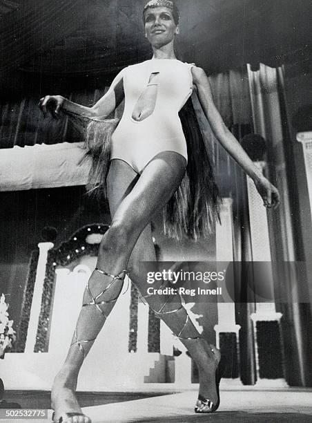 Fabulous model Veruschka moves like a ballet dancer. Knee-length hair; a cut-out front white swimsuit; gold leg-laced Roman sandals