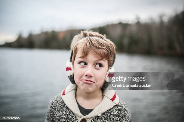 young boy making silly face wearing earmuffs - angela auclair stock pictures, royalty-free photos & images