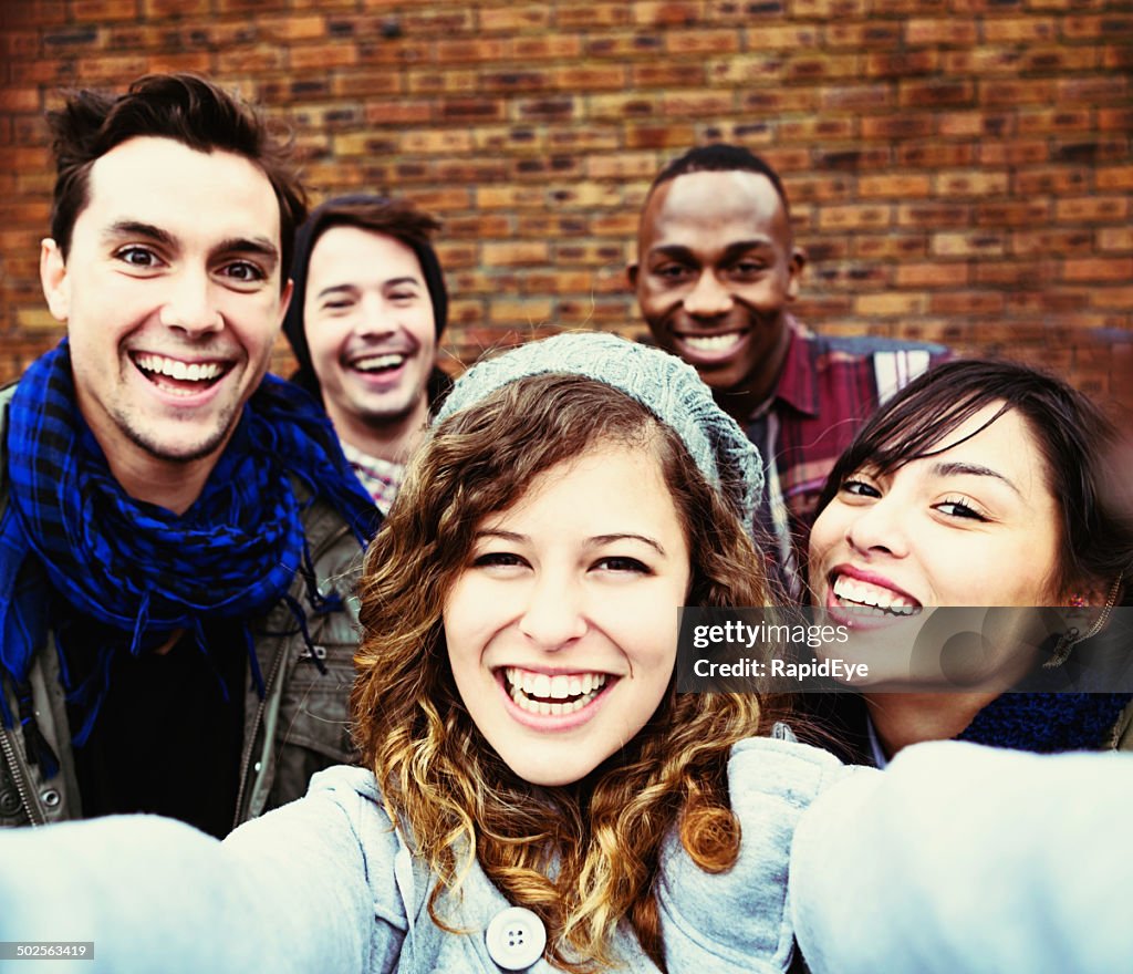 Five happy young people take smiling selfie