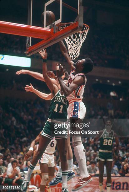 Caldwell Jones of the Philadelphia 76ers blocks the shot of Charlie Scott of the Boston Celtics during an NBA basketball game circa 1977 at The...