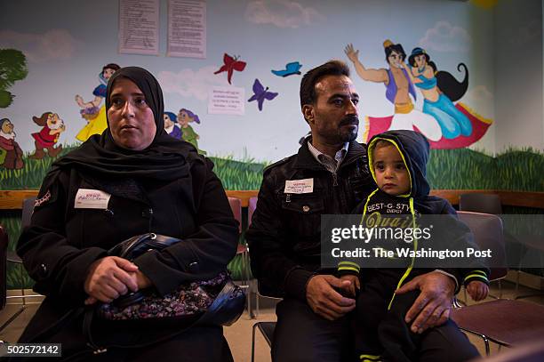 Houria Al Zakri and Sarhan Aldobai holding Alaa Nour Eddin Aldabbi sit in the waiting room to sign up for the Supplemental Nutrition Assistance...