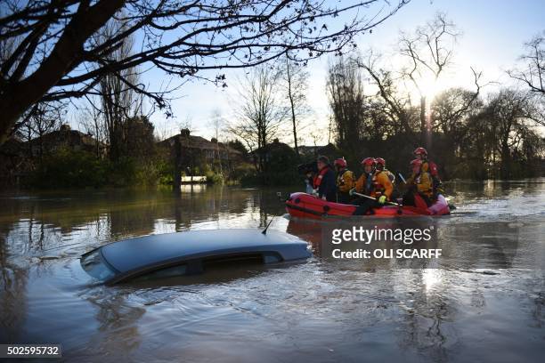 Members of the emergency services paddle down Huntington Road past a submerged parked car after the adjacent River Foss burst it's banks in York,...