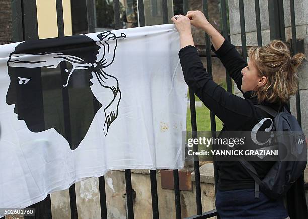 Woman hangs a Corsican flag on the gate of the prefecture in Ajaccio on December 27 after France banned demonstrations in part of the Corsican...