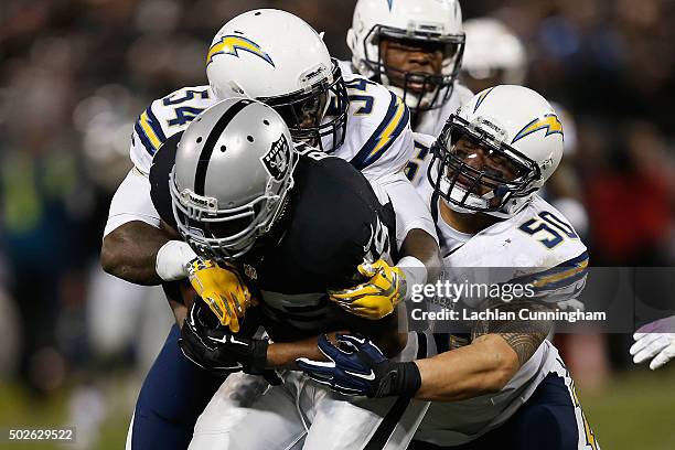 Full back Marcel Reece of the Oakland Raiders is tackled by linebackers Melvin Ingram and Manti Te'o of the San Diego Chargers in overtime at O.co...