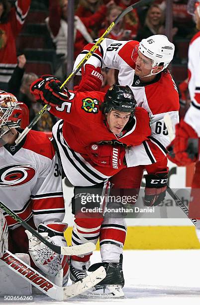 Andrew Shaw of the Chicago Blackhawks is grabbed in front of the goal by Ron Hainsey of the Carolina Hurricanes at the United Center on December 27,...