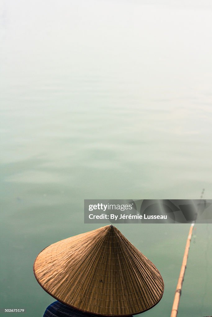 A woman with a chinese hat and a fishing pole