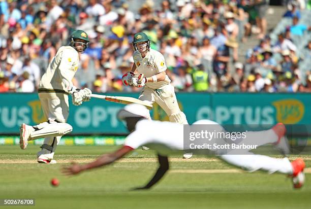 Steven Smith and Usman Khawaja of Australia run between the wickets as Kemar Roach of the West Indies dives for the ball during day three of the...