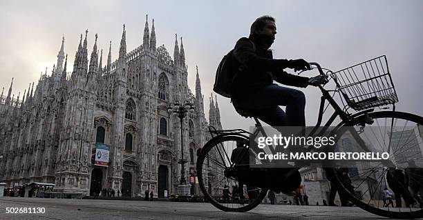 Man rides his bike near the Duomo in Milan on December 28, 2015. Drivers in Milan will face a limit on daytime travel three days as the northern...