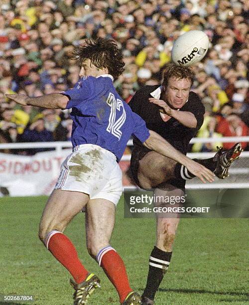 Le demi d'ouverture néo-zélandais, Grant Fox, dégage le ballon sous la pression du trois-quarts centre français Denis Charvet, le 20 juin 1987 à...
