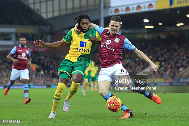 Dieumerci Mbokani of Norwich City and Ciaran Clark of Aston Villa compete for the ball during the Barclays Premier League match between Norwich City...