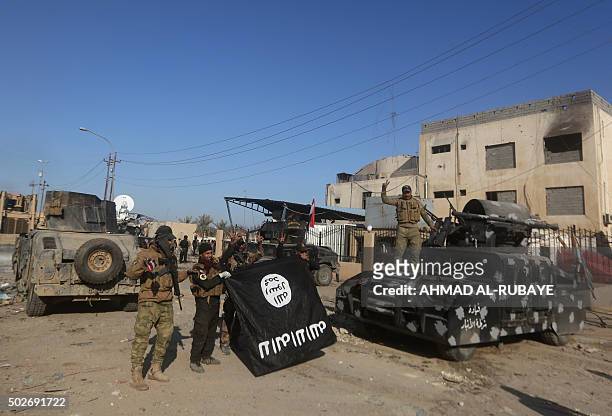 Members of Iraq's elite counter-terrorism service hold the Islamic State group's flag and flash the "V" for victory sign on December 28, 2015 after...