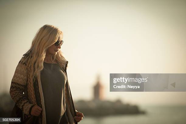 attractive mature woman in woolen clothings walking - slovenia beach stock pictures, royalty-free photos & images