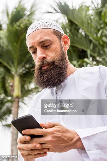 middle eastern man looking at his smart phone - imam stock pictures, royalty-free photos & images