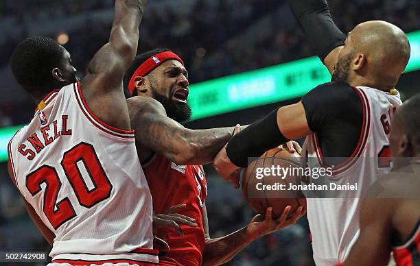 James Johnson of the Toronto Raptors tries to get off a shot between Tony Snell and Taj Gibson of the Chicago Bulls at the United Center on December...