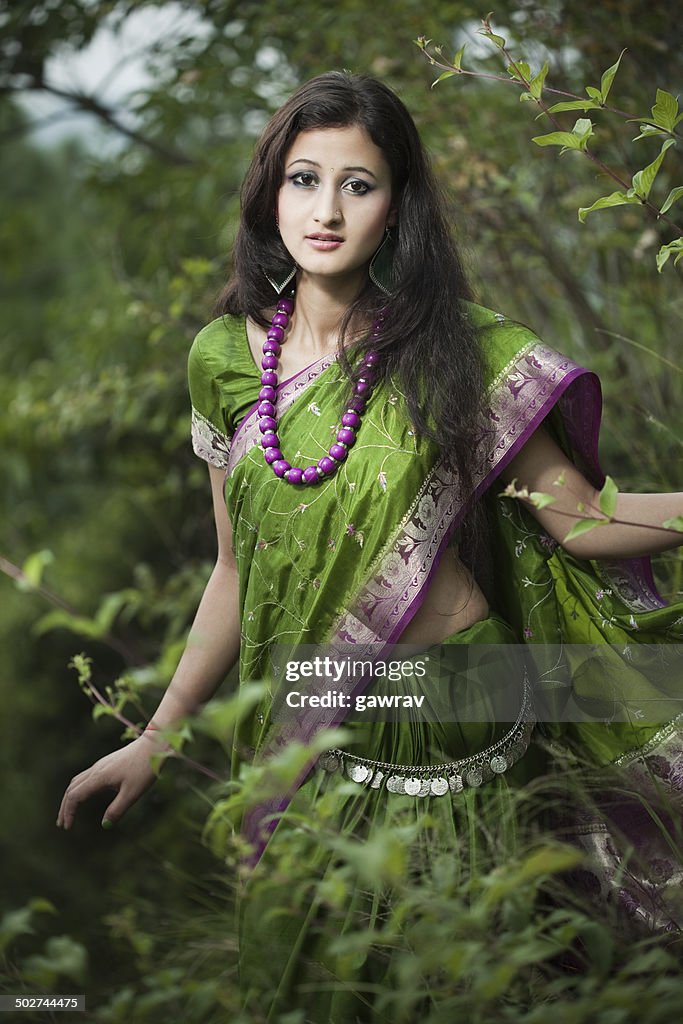 Beautiful young woman in green sari between nature.