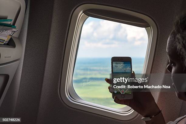 Tourist woman taking picture with cell from an airplane taking off in Cuba .