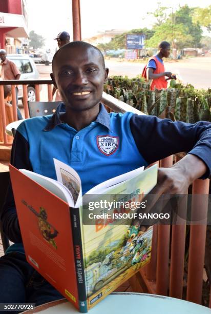 Central African cartoonist Didier Kassai presents on December 29, 2015 in Bangui, his new animated book "Tempete Bangui" which sets the stage...