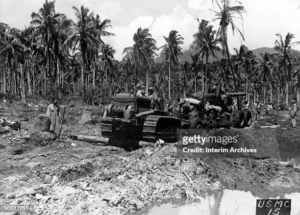 Marines usa a tractor to pull a 155mm field gun along a debris-strewn beach, Rendova Island, Solomon Islands, 1943.