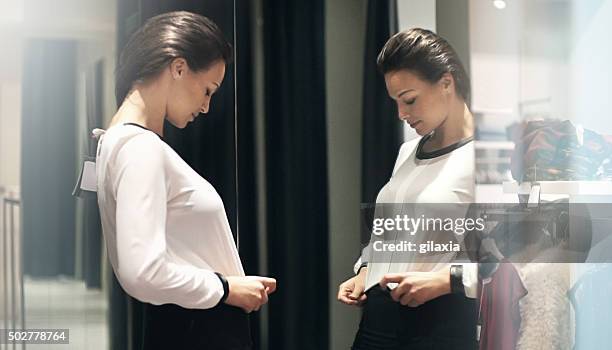 frau versuchen, auf die kleidung in einem geschäft. - white blouse stock-fotos und bilder