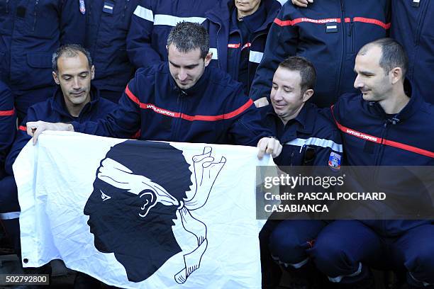 Firemen hold the Corsican flag during a rally at the Ajaccio's central Fire Station on December 29, 2015 to show their solidarity and support...