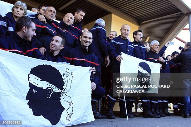 Firemen hold the Corsican flag during a rally at the Ajaccio's central Fire Station on December 29, 2015 to show their solidarity and support...