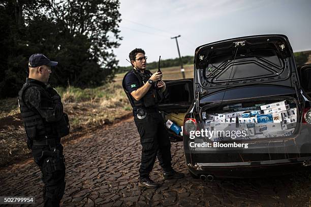 Brazilian Tax Authority agent uses a radio to communicate to colleagues that he has discovered a load of smuggled cigarettes near the border with...