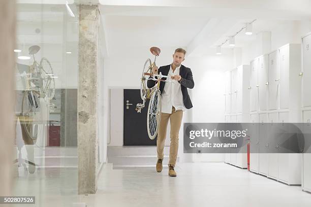 geschäftsmann, tragen seine fahrrad im büro - spind stock-fotos und bilder