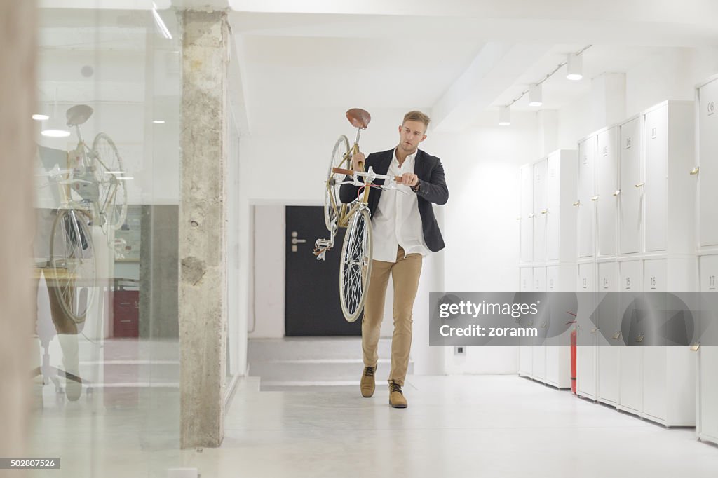 Businessman carrying his bicycle in office