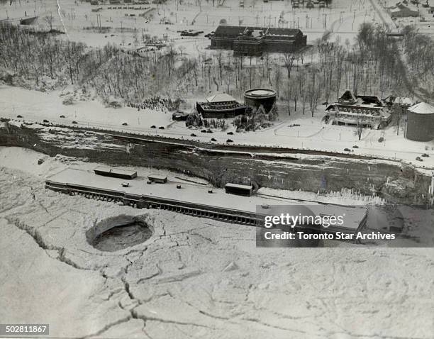 New floes sweep over falls to add weight to jam squeezing 700-foot building; Ice blocks are pouring over the Horseshoe Falls at Niagara again to-day...