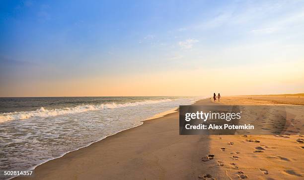 two girls running at the jones beach at the sunset - long island stock pictures, royalty-free photos & images