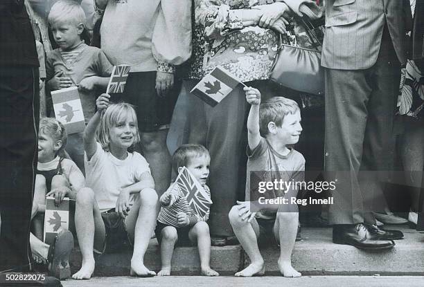 Young fans of the Queen sit on the curb near the Royal York Hotel; waving canadian flags and Union Jacks as she left; in the Ontario landau; for...