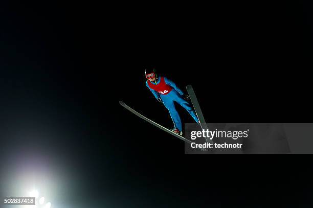 night shot of ski jumper in mid-air - ski jump stock pictures, royalty-free photos & images