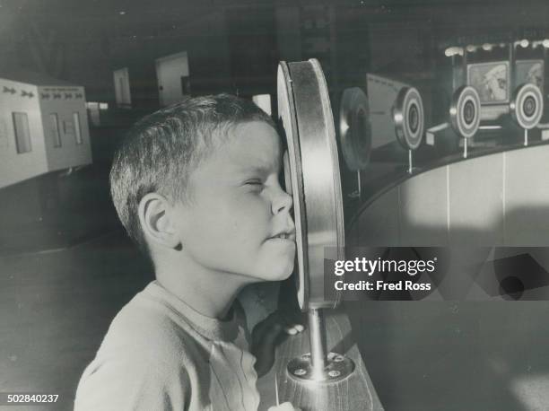 Optics. Another visitor; Garry Derry; peers through an eyepiece which creates an optical illusion that a wooden bar is actually passing through...