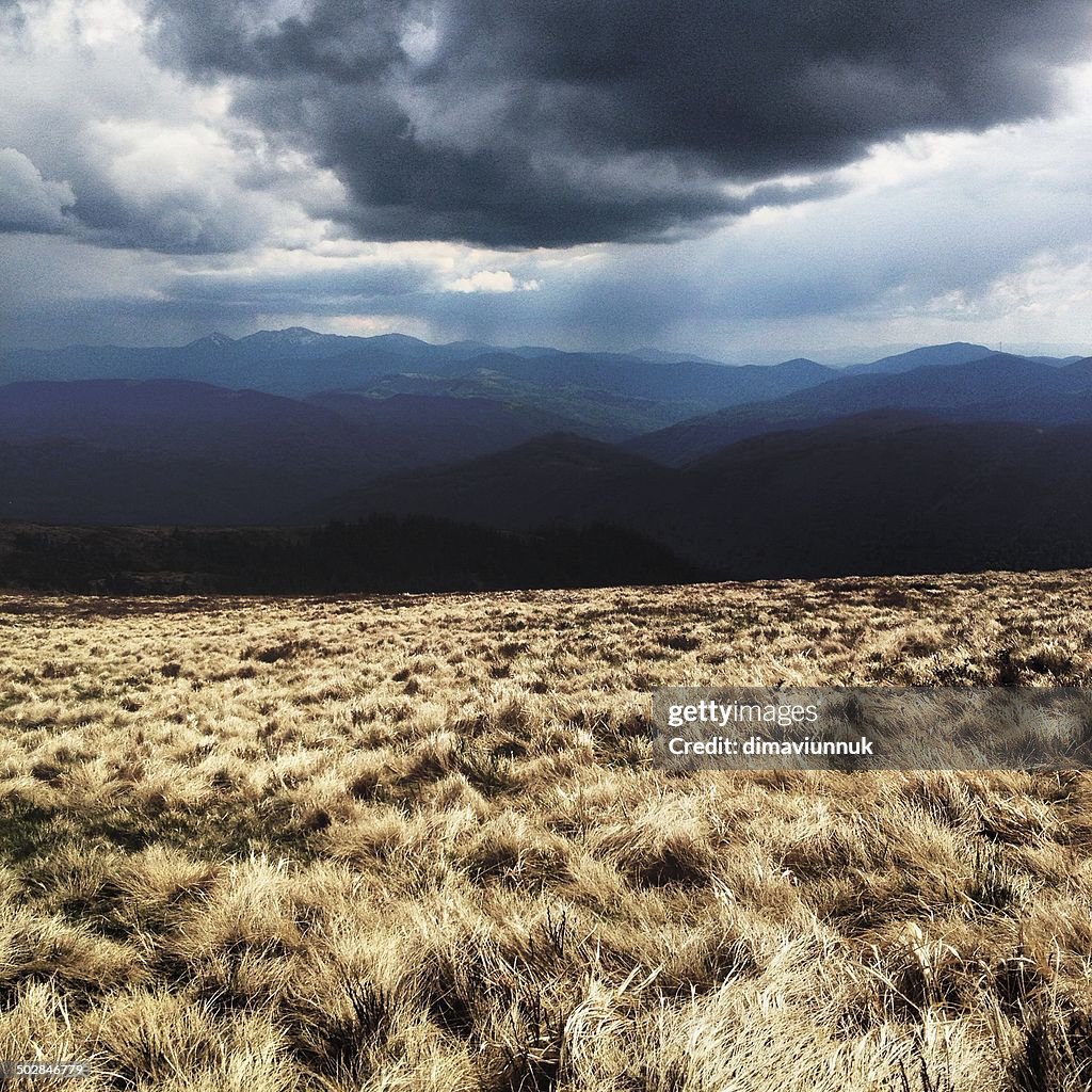 Heavy cloud over field and mountains