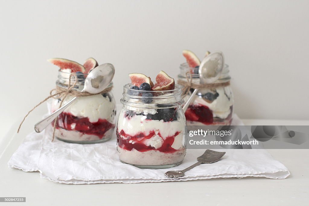 Eton mess desserts in jars topped with fresh figs and blueberries