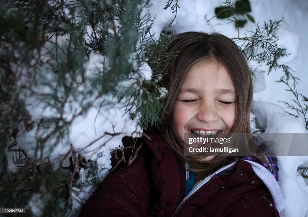 Girl standing by snow covered trees laughing