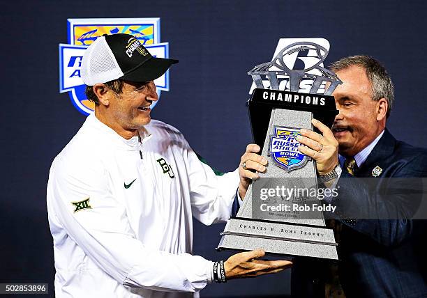 Robert Davis, vice president and GM of Russell Athletic, hands the chapionship trophy to head coach Art Briles of the Baylor Bears after the Russell...