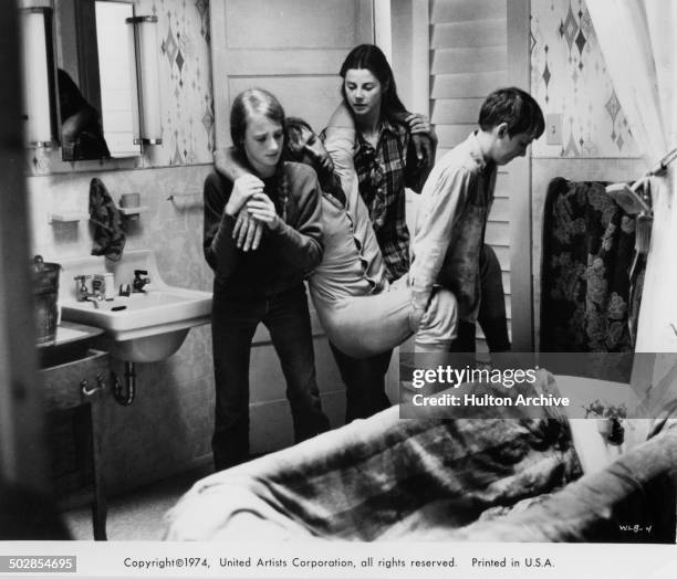 Julie Gholson, Jan Smithers and Matthew Burrill carry pneumonia stricken Harry Dean Stanton in a scene for the United Artist movie "Where the Lilies...