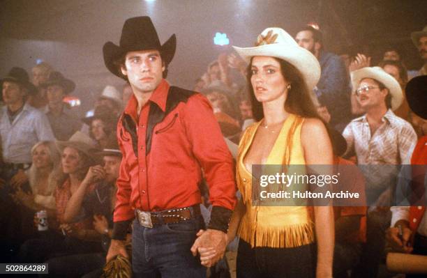 Actor John Travolta and Madolyn Smith Osborne walk in a scene of the Paramount Pictures movie 'Urban Cowboy" circa 1980.