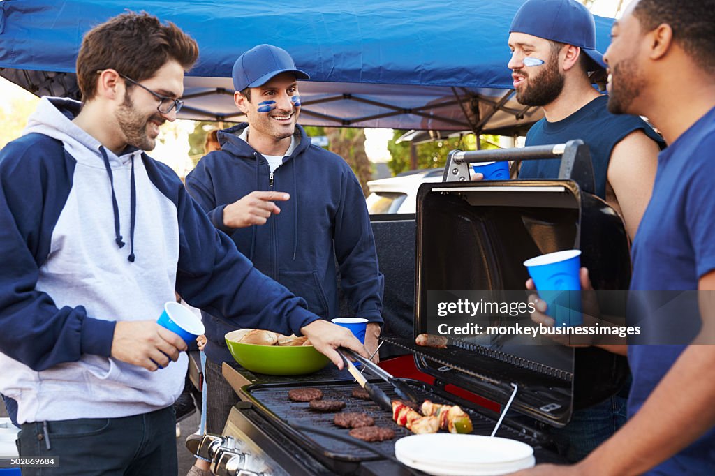 Group Of Male Sports Fans Tailgating In Stadium Car Park