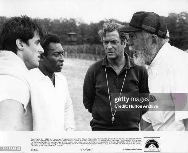 Director John Huston talks with Sylvester Stallone, Michael Caine and Pele behind the scenes for the Paramount Pictures movie "Victory" circa 1980.