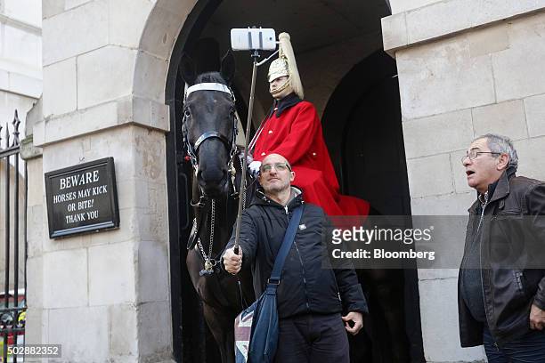 Tourist use a smartphone on a selfie-stick to take a selfie with a member of the armed forces on the Horse Guards Parade in London, U.K., on Tuesday,...