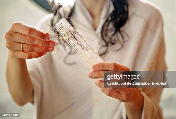 hair loss.hands holding a comb full of hair fallen - pérdida de pelo fotografías e imágenes de stock