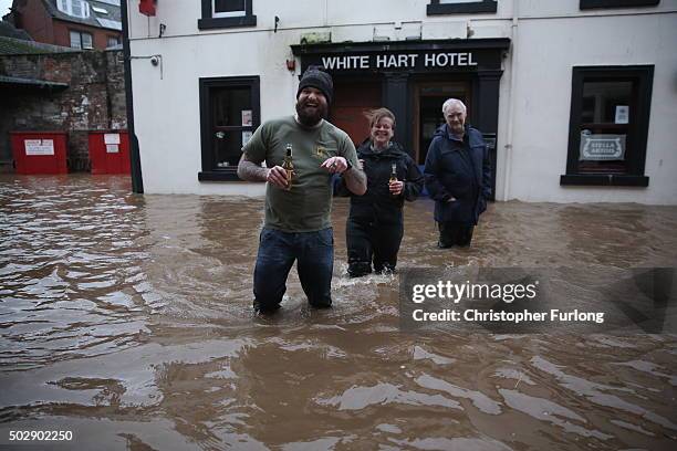 People wade through the water to get to the White Hart Hotel as the River Nith bursts its banks on December 30, 2015 in Dumfries, Scotland. Severe...