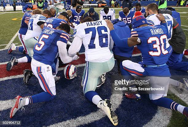 Greg Hardy of the Dallas Cowboys joins Tyrod Taylor of the Buffalo Bills in a prayer circle after their NFL game at Ralph Wilson Stadium on December...