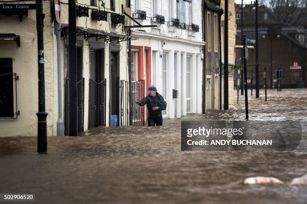 Man wades in floodwater in a street in Dumfries, southern Scotland, on December 30, 2015 after heavy rainfall brought by Storm Frank. Storm Frank...