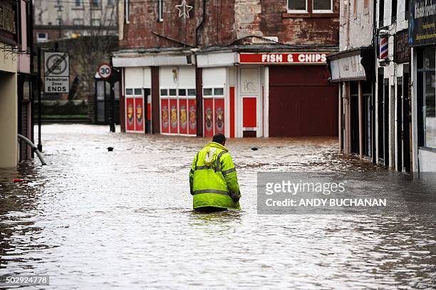Man wades through floodwater in a street in Dumfries, southern Scotland, on December 30, 2015 after heavy rainfall brought by Storm Frank. Storm...